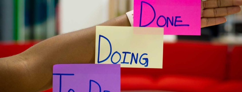To do, doing, done signs on post it notes on person arm.
